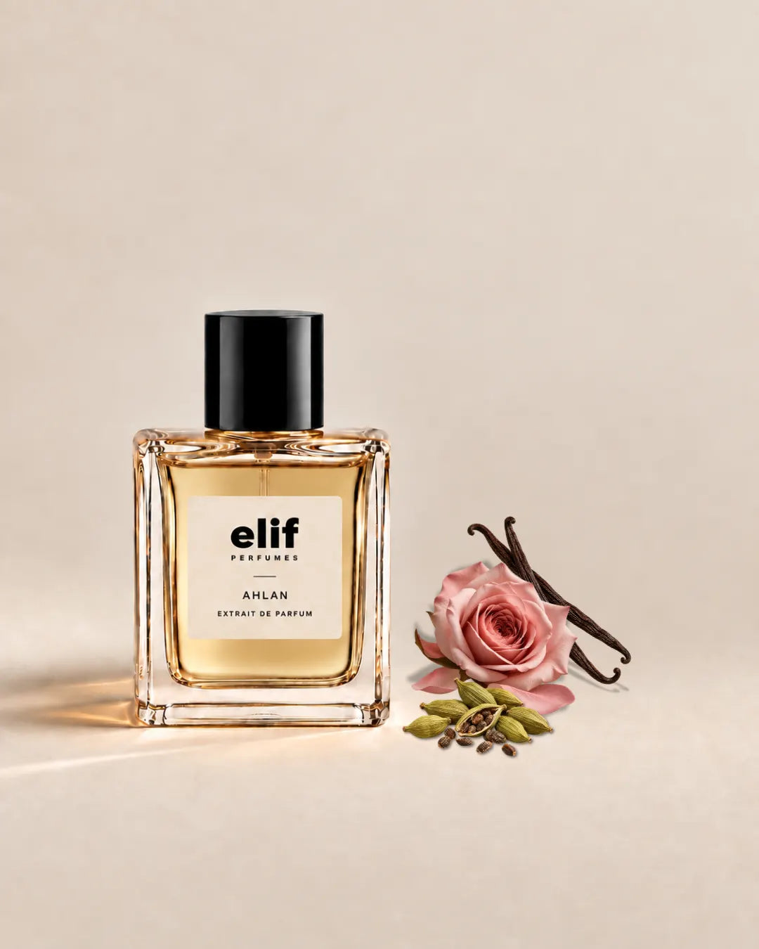 Elif Ahlan perfume bottle filled with warm golden liquid and topped with a glossy black cap, set against a soft beige background. A pink rose, vanilla pods, and green cardamom pods are arranged beside the bottle, with warm directional lighting and subtle shadows.