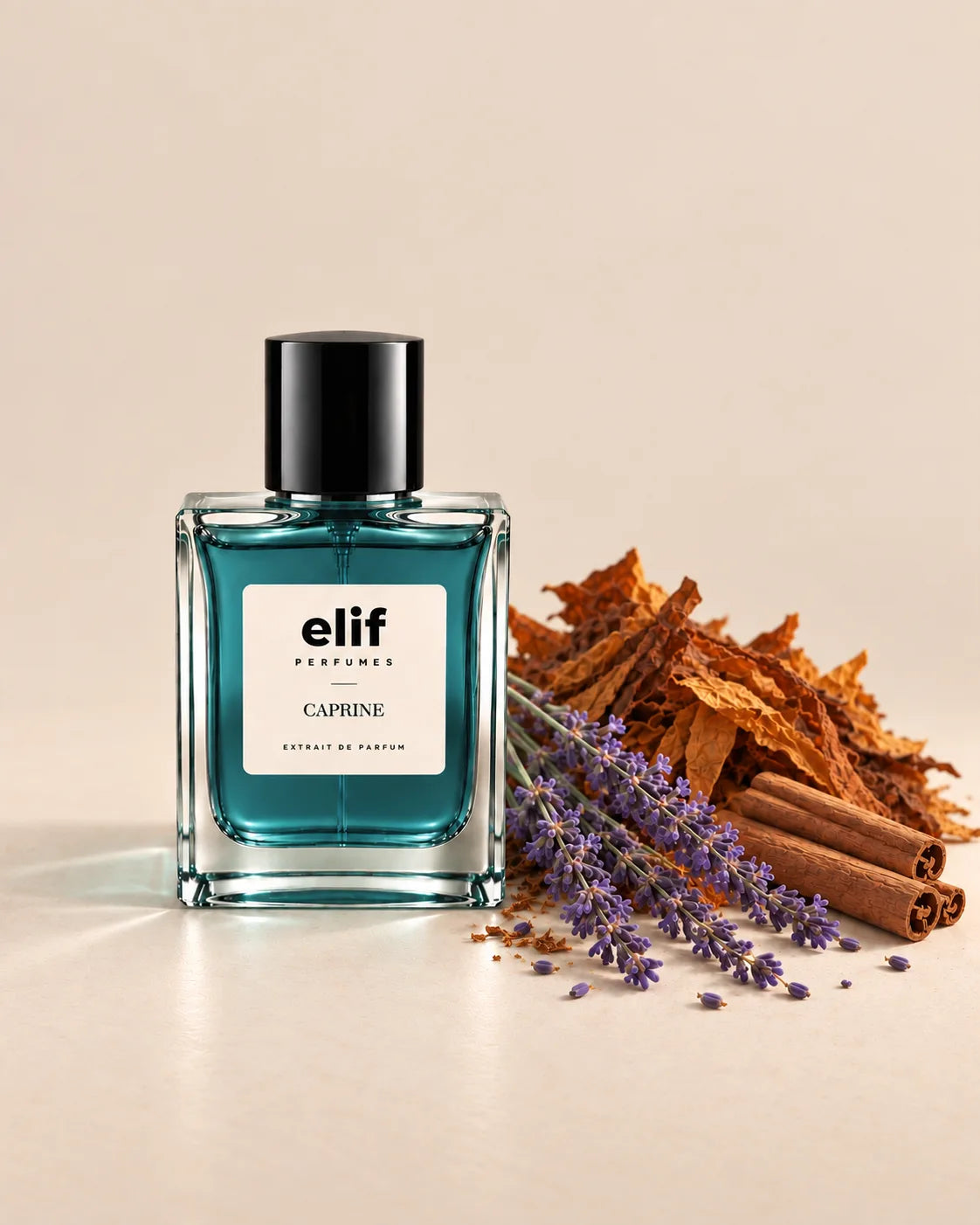 Elif Caprine perfume bottle with deep teal-blue liquid and a black cap, displayed against a warm beige background. Dried tobacco leaves, fresh lavender sprigs, and cinnamon sticks are arranged beside the bottle, creating a warm, aromatic composition. Soft natural lighting casts subtle shadows across the surface. A long-lasting fragrance with a warm, spicy, woody, and aromatic character.