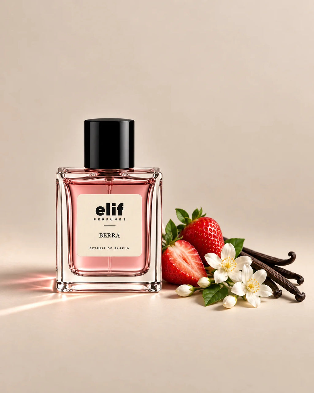 Elif Berra perfume bottle filled with soft pink liquid and topped with a glossy black cap, displayed against a warm beige background. Fresh strawberries, white jasmine flowers, green leaves, and dark vanilla pods are arranged beside the bottle, with warm directional lighting and subtle shadows.