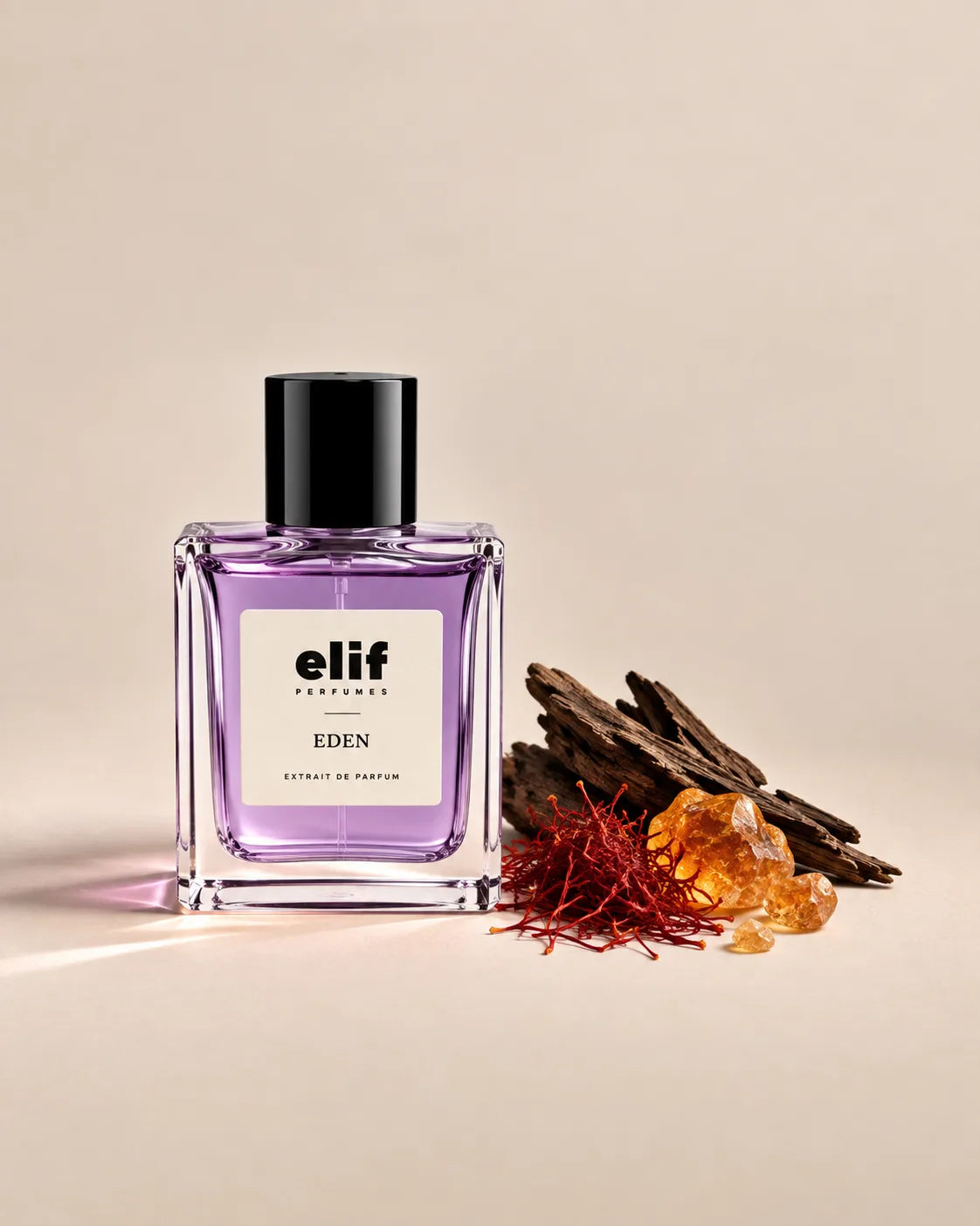 Elif Eden perfume bottle filled with translucent lavender-purple liquid and topped with a glossy black cap, displayed against a warm beige background. Dark oud wood, saffron threads, and golden amber resin are arranged beside the bottle, with soft directional lighting and subtle shadows.