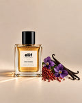 Elif Nocturne perfume bottle filled with warm amber-gold liquid and topped with a glossy black cap, displayed against a warm beige background. Purple violet flowers, red berries, and dark vanilla pods are arranged beside the bottle, with warm directional lighting and subtle shadows.