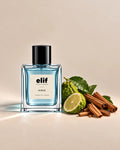 Elif Surge perfume bottle filled with translucent icy blue liquid and topped with a glossy black cap, displayed against a warm beige background. A green bergamot fruit, sliced citrus, fresh green leaves, and cinnamon sticks are arranged beside the bottle, with soft directional lighting and subtle shadows.