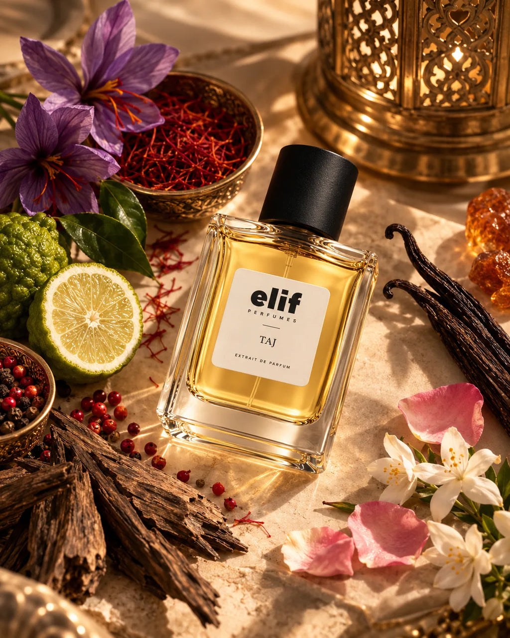 A bottle of elf perfume with a black cap and a white label reading 'Elif perfume TAJ', surrounded by saffron, purple flowers, a lime slice, vanilla beans, amber crystals, and dried roots on a warm neutral surface.